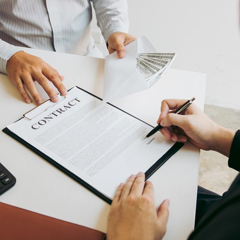 Entrepreneurs are signing a contract about business under fraud while colleagues give money in an envelope.