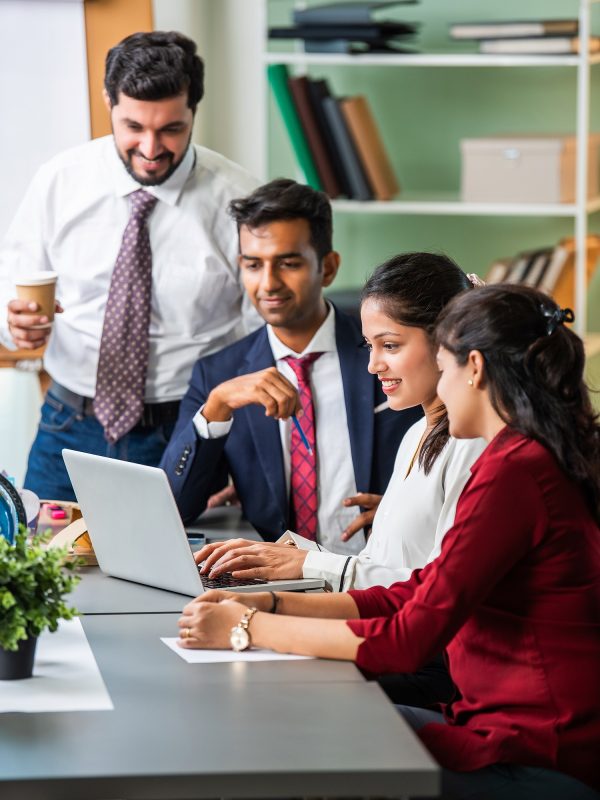 Indian asian young business professionals using laptop on desk discussing strategy