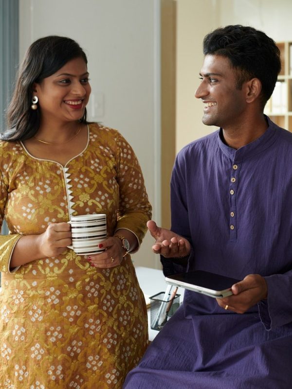 Smiling Indian business colleagues in traditional clothes discussing work during coffee break